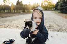 Portrait Of Cute Boy Carrying Cat At Park