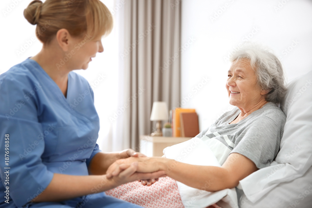 Caregiver massaging hand of senior woman at home - obrazy, fototapety, plakaty 