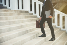 Businessman Wearing Black Suit And Holding Bacg Walking Up The Stair