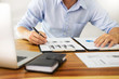 © snowing12 - business men working on wooden desk(table) with notebook computer paper, pencil and hand in office, financial concept.
