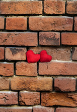 Two Knitted Red Heart On A Crumbling Old Red Brick Textured Wall Vertically