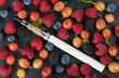 electronic cigarette in the center of a background of small berries