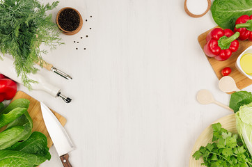 Healthy vegeterian ingredients for spring fresh green salad and kitchenware on white wood board, top view, copy space.