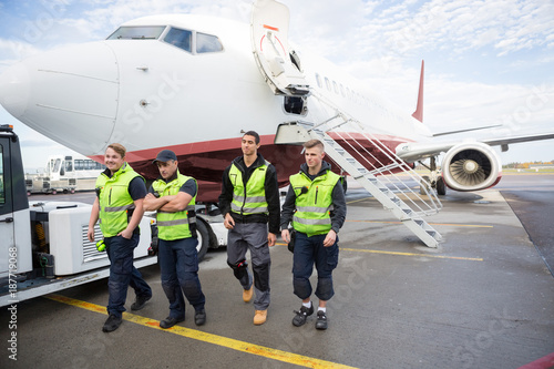 Foto Confident Ground Crew Walking Against Airplane