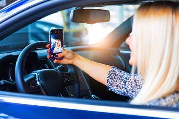 Young woman driver taking a selfie in her car