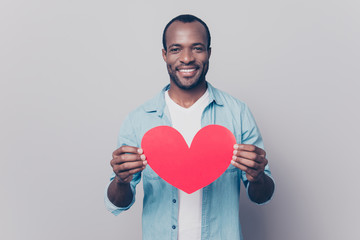 Be my girlfriend! I love you! Portrait of tender gentle romantic sweet lovely open-hearted african man showing big red heart in hands isolated on gray background