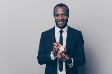 Will you be my woman wife? Portrait of happy smiling excited romantic loving afro guy making an offer marriage opening red box with diamond golden ring isolated on gray background