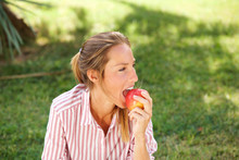Beautiful Young Woman Eating Apple In The Park