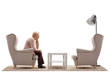 Wall Mural - Depressed and lonely mature woman sitting in an armchair