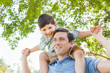 Wall Mural - Mixed Race Father and Son Playing Piggyback Together in the Park.