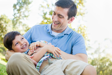 Wall Mural - Loving Young Father Tickling Son in the Park.