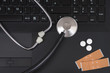a stethoscope, pills and plaster on a laptop 