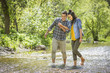 © Mike Kemp/Blend Images - Couple holding hands wading in river