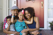 © Don Mason/Blend Images - Portrait of smiling mixed race family sitting on front stoop