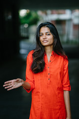 Wall Mural - Portrait of attractive and young Indian woman in an orange ethnic dress during the day