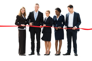 Businesspeople Cutting Red Ribbon With Scissors