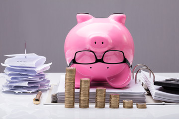 Stacked Coins In Front Of Upside Down Piggy Bank