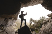 Hiker Standing At The Cave Entrance Taking Photos