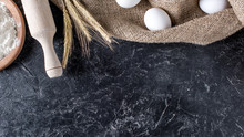 Flat Lay With Wheat, Raw Eggs On Sack Cloth And Wooden Rolling Pin On Dark Marble Surface