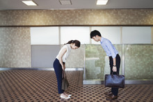 Two People Greeting, A Man And Young Woman Bowing From The Waist When They Meet In A Subway. 