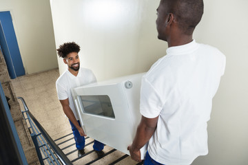 Wall Mural - Young Movers Carrying Cabinet While Climbing Steps