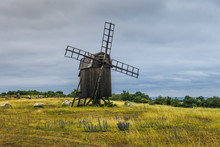 Old Wooden Windmill Standing On A Green Field By The Coast