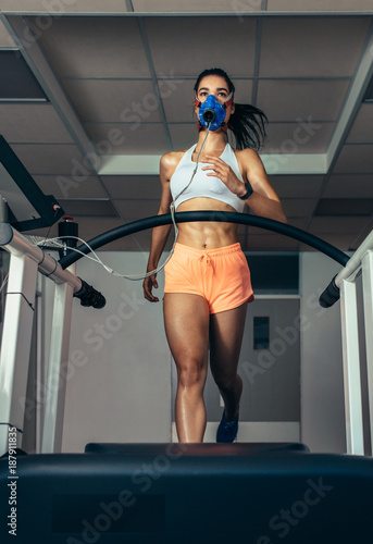 Fotografía Runner with mask on treadmill in sports science laboratory