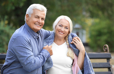 Poster - Mature couple sitting on bench outdoors