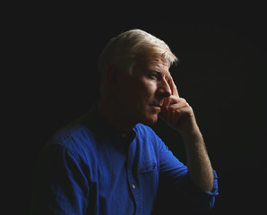 Wall Mural - Portrait of thoughtful mature man on dark background