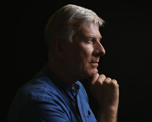 Wall Mural - Portrait of thoughtful mature man on dark background