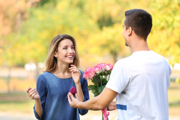 Wall Mural - Young man with engagement ring making proposal of marriage to his girlfriend in park