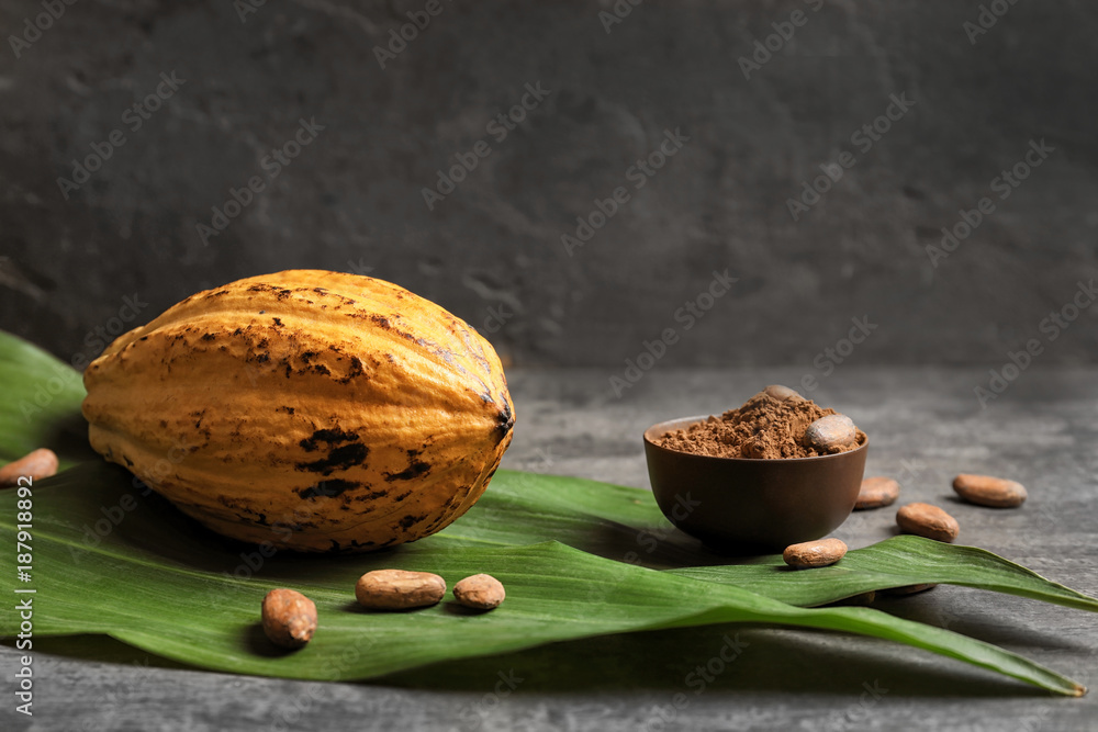Ripe yellow cocoa pod and bowl with powder on table