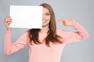 Sticker - Young woman with blank sheet of paper on grey background