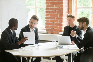 Canvas Print - African investment advisor consulting diverse businessmen, partners listening to black consultant holding showing document, making offer, presenting project plan at corporate executive team meeting