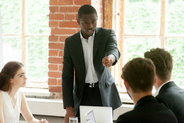 Wall Mural - Rude impolite african businessman pointing finger at colleague on team meeting, angry black boss scolding white employee for bad work, multiracial conflict at workplace, obnoxious behavior in office