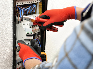 Wall Mural - Young electrician technician at work on a electrical panel with protective gloves