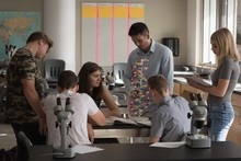 Teacher Assisting Students In Experiment On Molecule