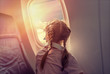 little cute girl in airplane looking clouds in the window