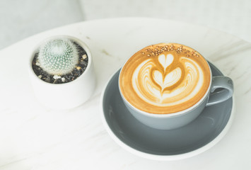 Wall Mural - Cappuccino coffee with tree latte art in blue coffee cup on white marble table in perspective view in cafe,modern lifestyle leisure