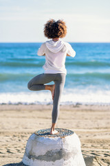 Wall Mural - Rear view of young black woman doing yoga in the beach