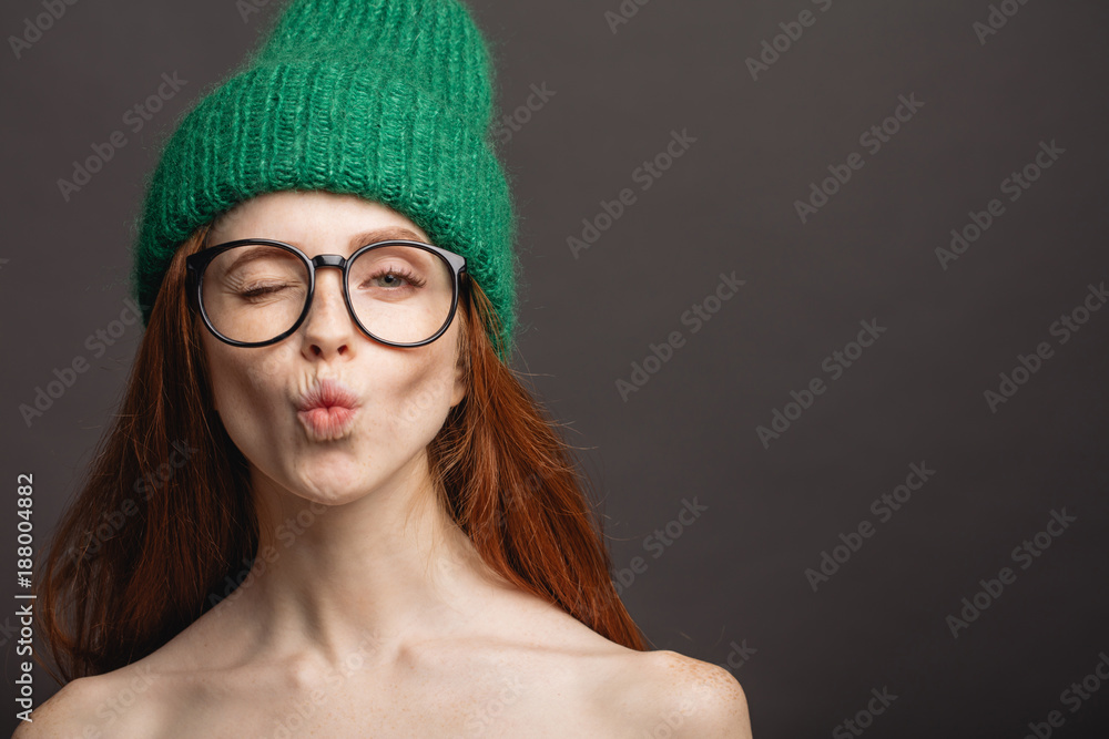 Foto de Stock naked ginger woman wearing circle glasses and green hat pouting her lips ready for