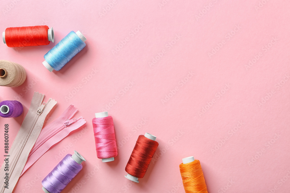Set of sewing threads with zippers on color background, top view
