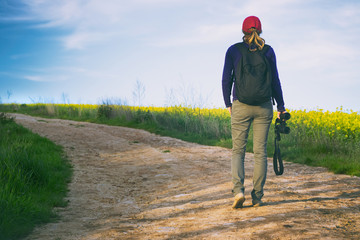 traveler woman with binoculars is walking on footpath in the fields