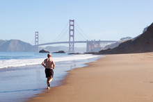 Old man running on baker beach close to Golden Gate bridge.