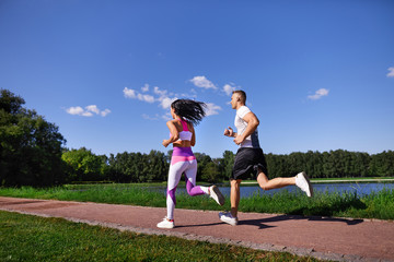 Man and woman doing Jogging in the Park near the water.