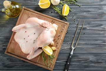 Poster - Fresh raw whole chicken with spices and lemon on wooden board