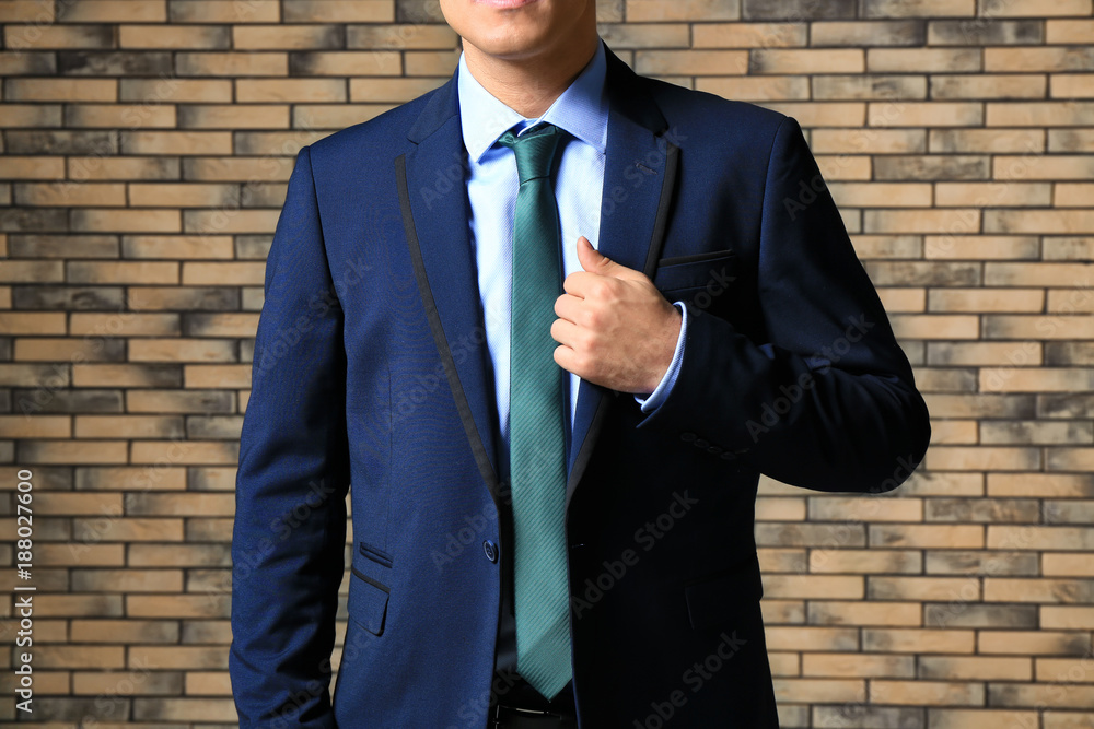 Handsome man in elegant suit near brick wall