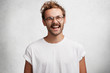 © wayhome.studio  - Positive pleased handsome stylih young man in round eyewear and casual t shirt, laughs at something funny, being in good mood as spends free time at circle of friends, expresses real happiness