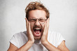 © wayhome.studio - Close up portrait of crazy stressful male screams in panic and terror, being fed up with everything, closes eyes in despair, yells loudly, isolated over white background. Emotions and feelings concept