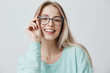 Cheerful female student in stylish eyewear rejoices successfully passed exams, glad to have meeting with groupmates. Delighted beautiful pleased woman has attractive look, poses indoors.